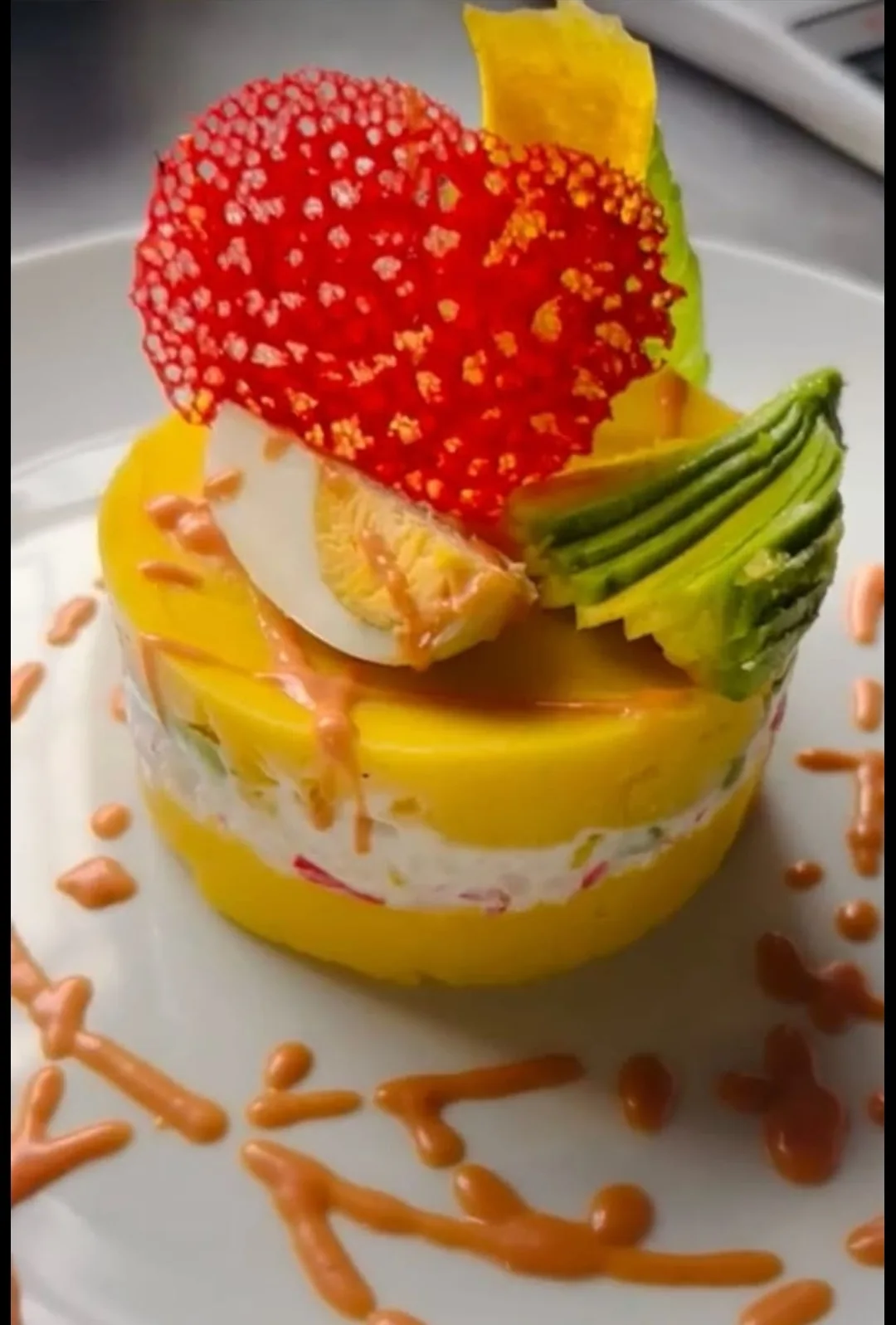 Layered yellow potato causa filled with a creamy salad, garnished with avocado fan, egg and crisp plantain at Peruvian Latinos
