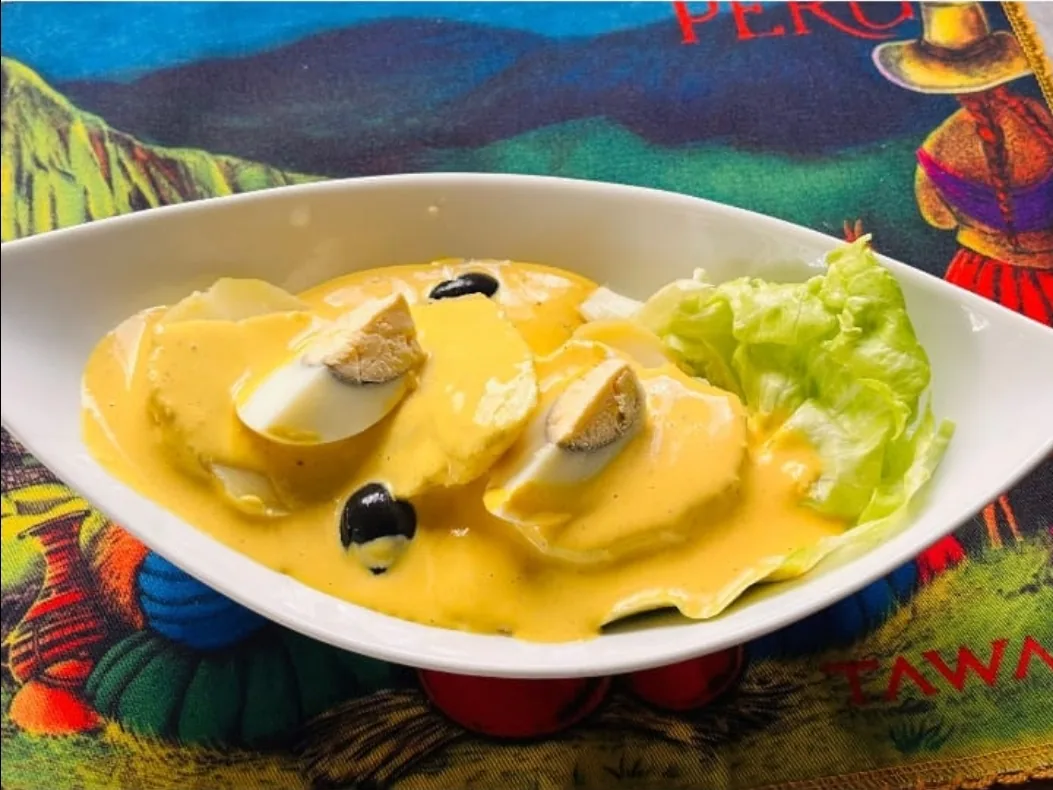 Peruvian dish in a creamy yellow ají sauce with sliced egg and black olives, served with lettuce at Peruvian Latinos