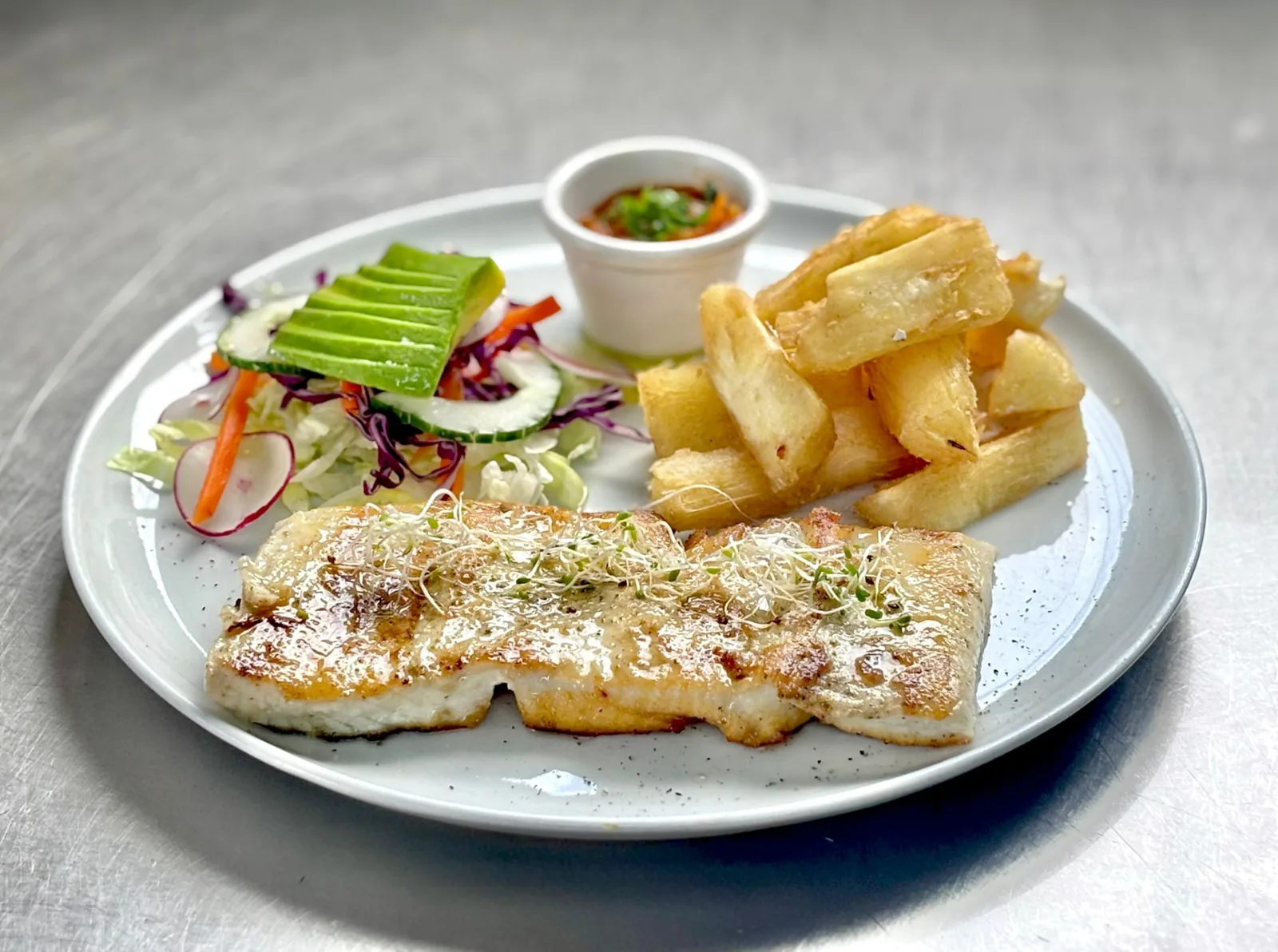 Grilled fish fillet with fried yuca, fresh salad, avocado and a side of salsa criolla at Peruvian Latinos