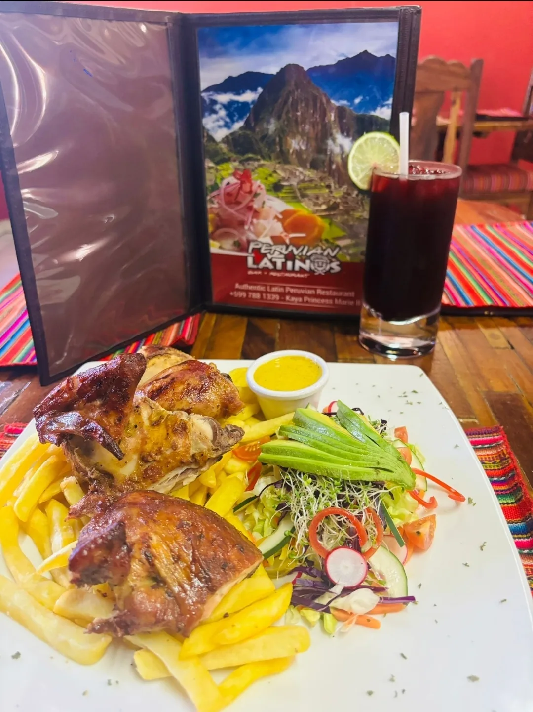 Table at Peruvian Latinos with roast chicken, fries and salad beside a glass of chicha morada and the restaurant's Peruvian Latinos menu