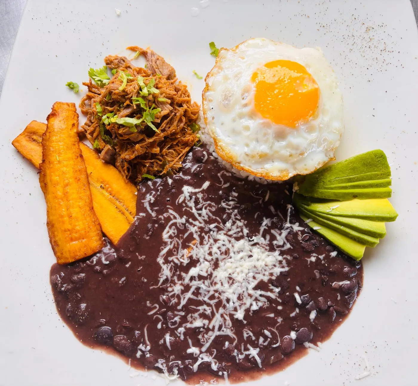 Pabellón Venezolano at Peruvian Latinos: shredded beef, white rice, black beans with cheese, fried egg, avocado slices and sweet fried plantain